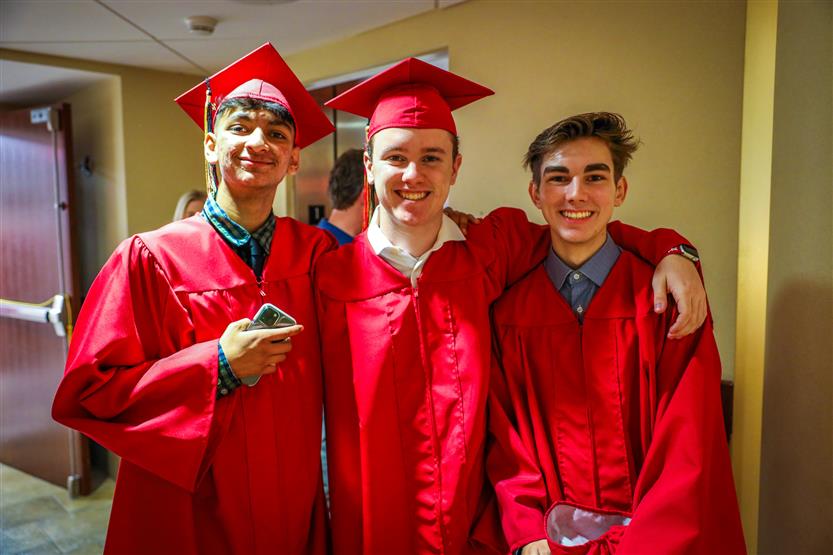 Students in red robes graduate